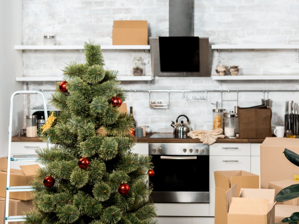 interior of kitchen with decorated christmas tree and cardboard boxes during relocation at new home