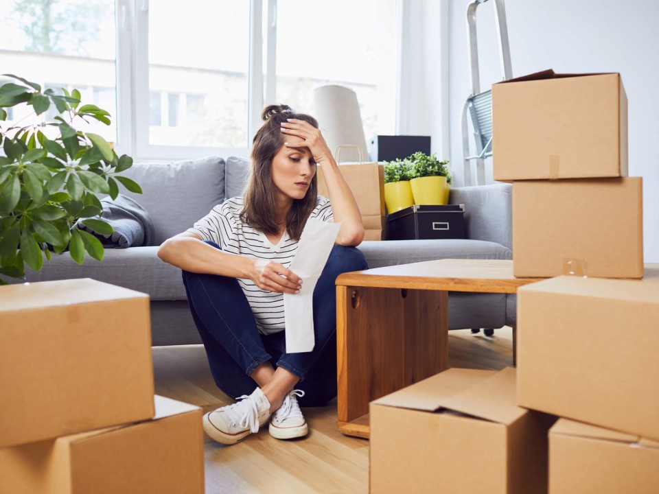 woman surrounded by packing boxes and home belongings