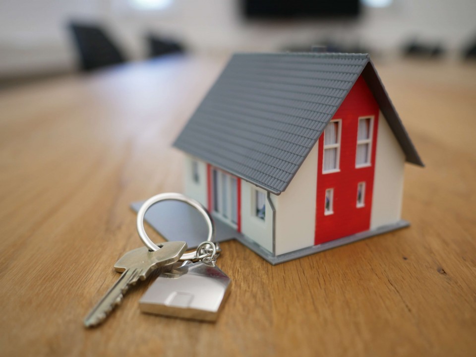 model house next to a set of keys on a wooden table