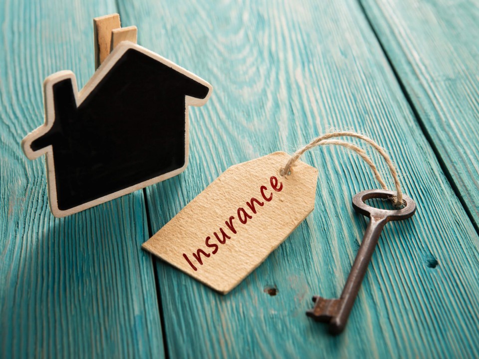key with insurance tag attached to it next to model house