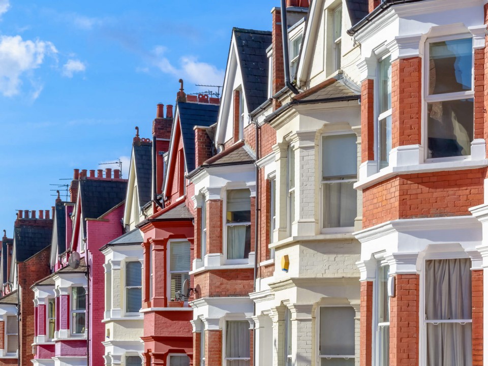 close up of row of terraced houses against the backdrop of a blue sky