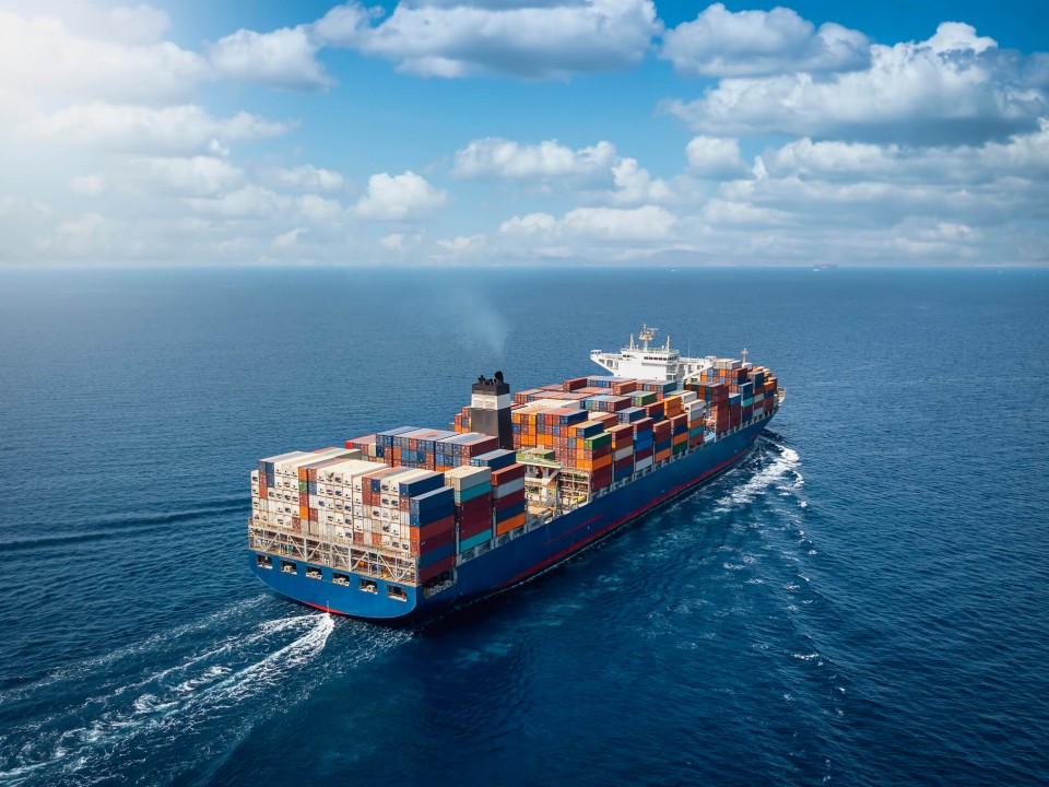 A large container cargo ship travelling over a blue ocean